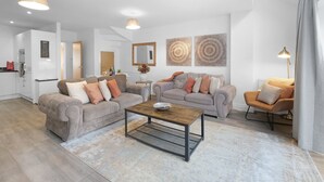 A modern living room with two sofas, a coffee table, and a dining area. - Spacious 6 Bedroom House in Denton Way (Slough)