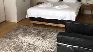 Un dormitorio con cama, armario, alfombra y un cuadro en la pared.
