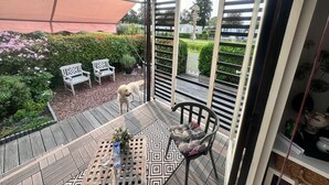A covered patio area with a table, chairs, and a dog. - Cozy chalet near the sea. Pet friendly! (Schagen)
