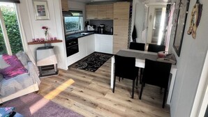 A compact living space with a kitchenette, a dining area, and a seating area with a sofa and a coffee table. - Cozy chalet near the sea. Pet friendly! (Schagen)