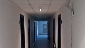 A long, narrow hallway with a tiled floor and white walls. There are doors on both sides, and a ceiling with recessed lighting. - Relax in Banya's Hidden Gem - Igzila Appartment (Razlog)