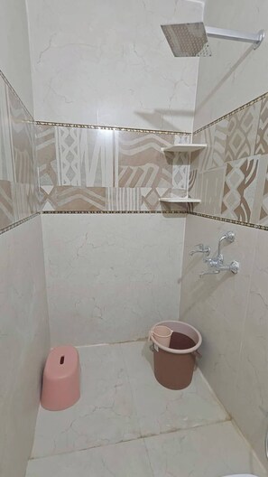 Une salle de bain avec une douche, des toilettes et un seau.