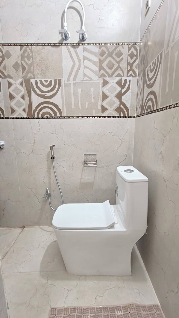 A bathroom with a toilet, a shower, and a towel rack. - ZM Homestay - Luxury Comfort Awaiting (Agra)