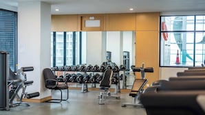 Un gimnasio con equipo de ejercicio, bancos y mancuernas.