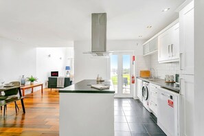 Eine moderne Küche mit einer zentralen Kochinsel, integrierten Geräten und einem Essbereich mit Tisch und Stühlen.