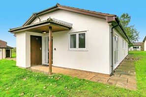 Una casa de un piso con puerta principal, un pequeño porche y una ventana.