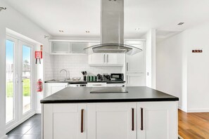 A modern kitchen with white cabinetry, a black countertop, and stainless steel appliances. - Bright & Modern 2 Bed Holiday Chalet nr Sidmouth (Sidmouth)