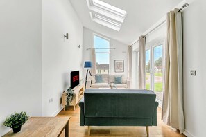 Un salon moderne avec un canapé, un téléviseur et une fenêtre avec des rideaux.