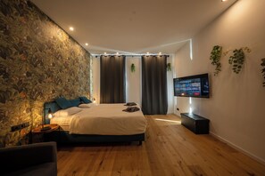 A modern bedroom with a large bed, a TV mounted on the wall, and a wooden floor. - Velvet Vienna - at Metro station U1 - 5 mins to Opera (Vienna)