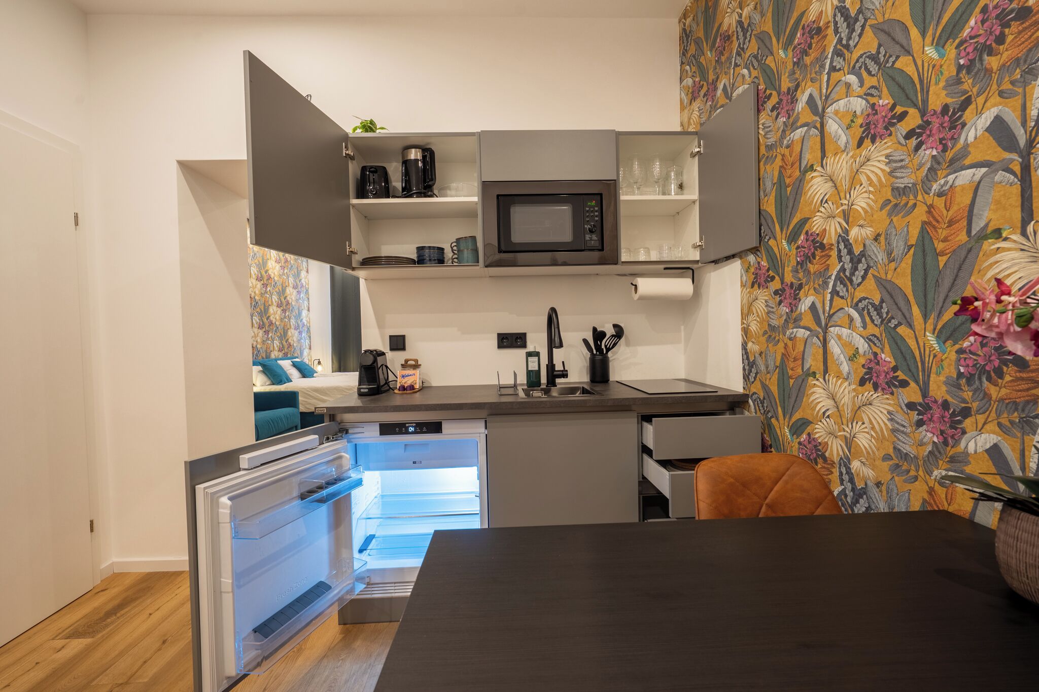 A compact kitchen with a built-in microwave, a coffee maker, and a dishwasher.