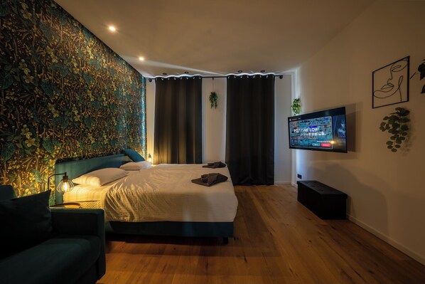 Une chambre à coucher moderne avec un grand lit, un téléviseur fixé au mur et un mur décoratif.