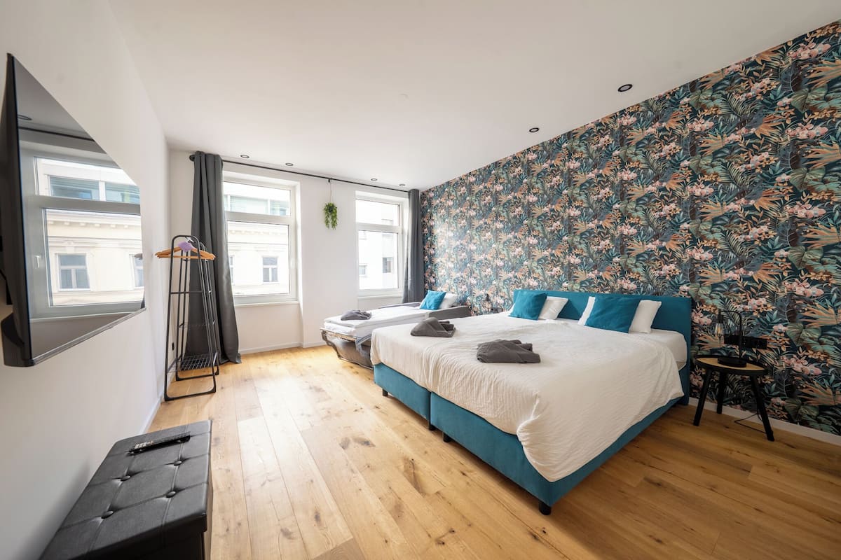 A bedroom with a large bed, a TV, and a window with curtains.
