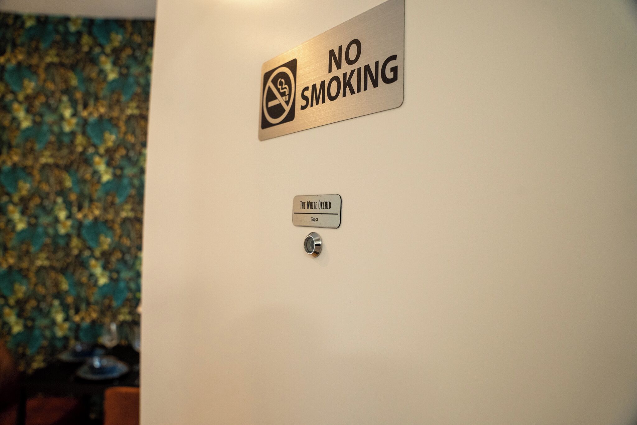 Un muro con il cartello 'No Smoking' e il cartello 'The White Orchid Top 3'.