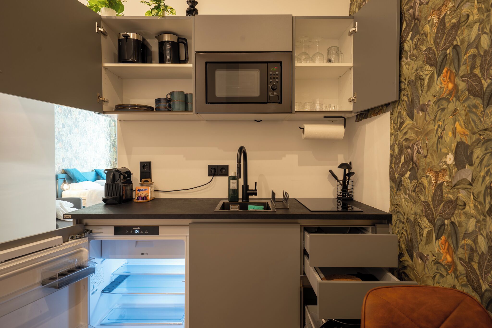 A compact kitchen with a built-in microwave, a coffee maker, and a sink.