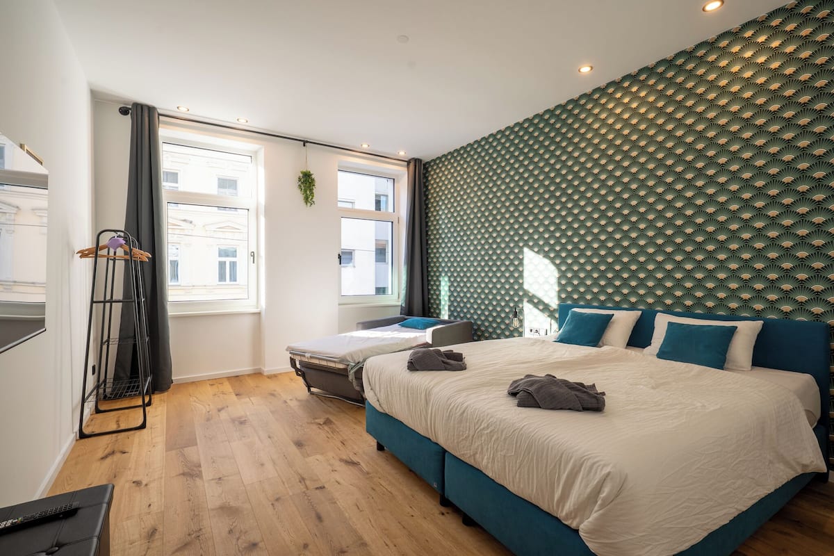 A modern hotel room with a large bed, a desk, and a window with curtains.