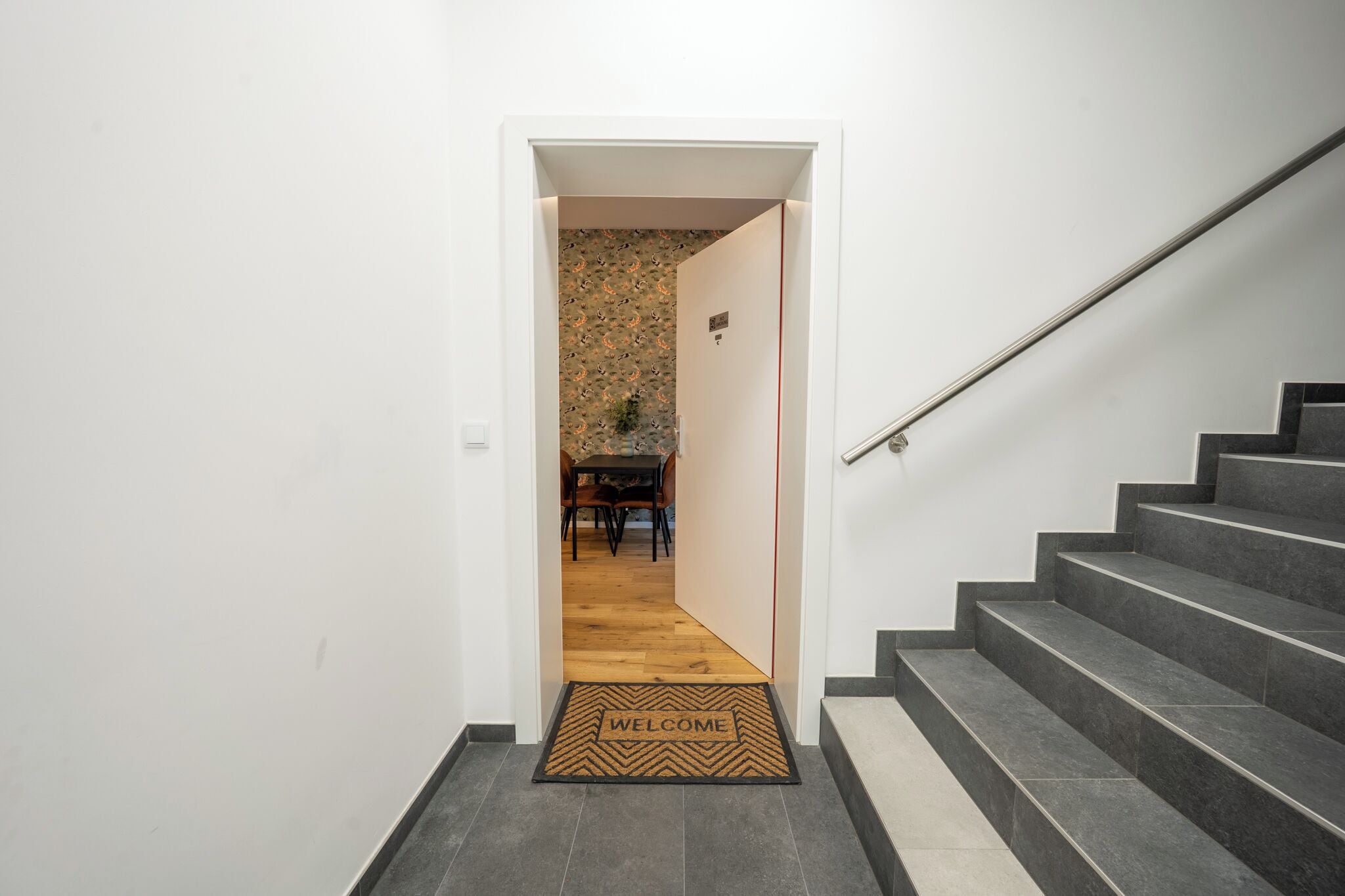 A staircase leading to a room with a 'WELCOME' mat.