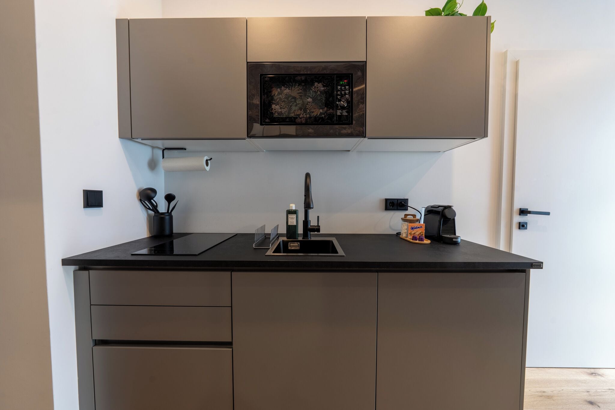 Una cocina moderna con microondas integrado, un lavabo y una cafetera.