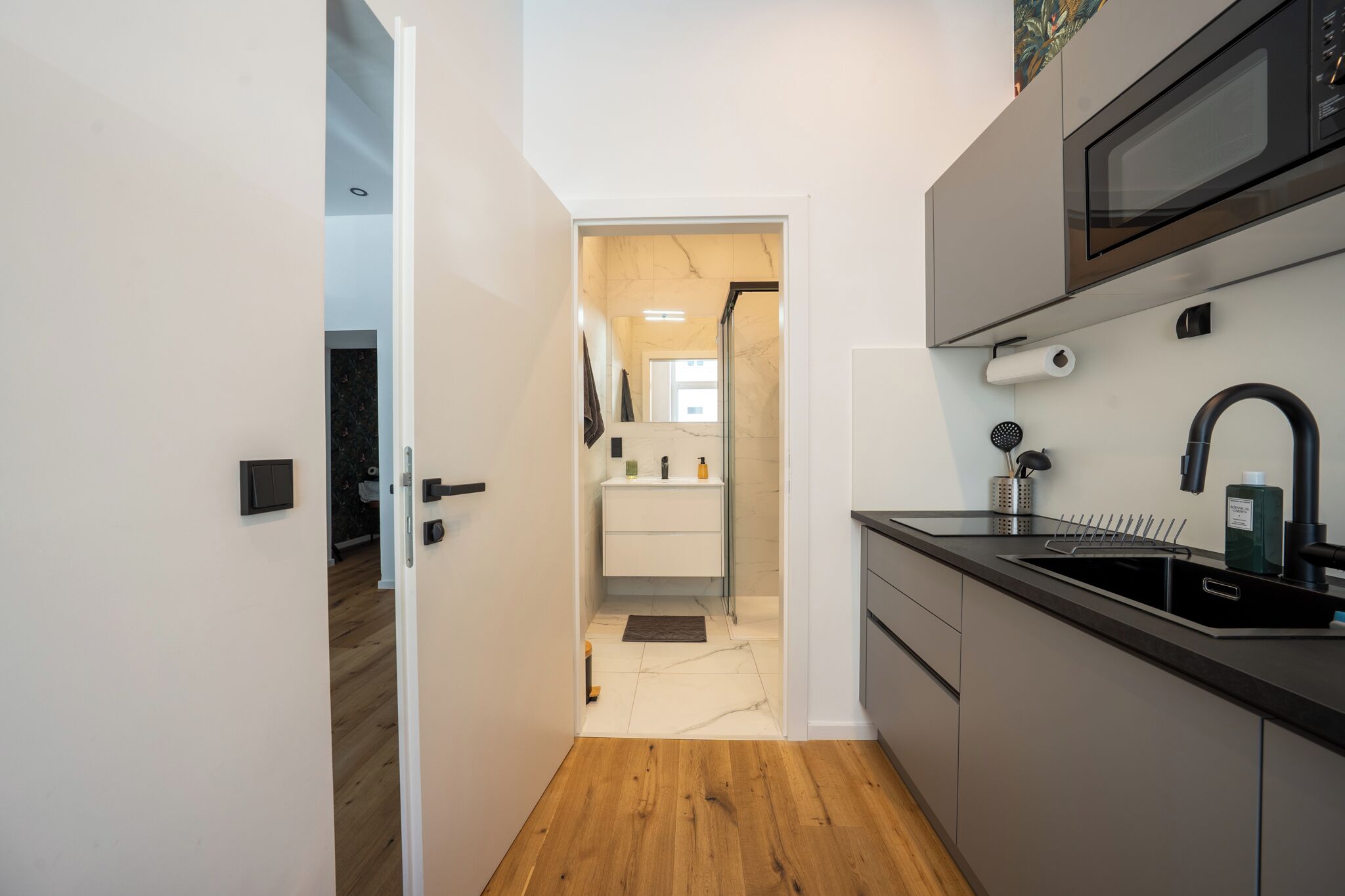 Cozinha moderna com micro-ondas embutido, pia e piso de madeira.