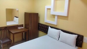 A hotel room with a bed, a wooden desk, a chair, a wardrobe, and a wall-mounted mirror. - Hotel Shrinivas Residency (Margao)