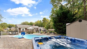 A backyard with a swimming pool, hot tub, and outdoor furniture.