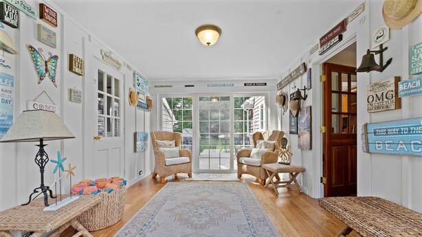 A cozy hallway with wicker furniture, a patterned rug, and various beach-themed signs on the walls.