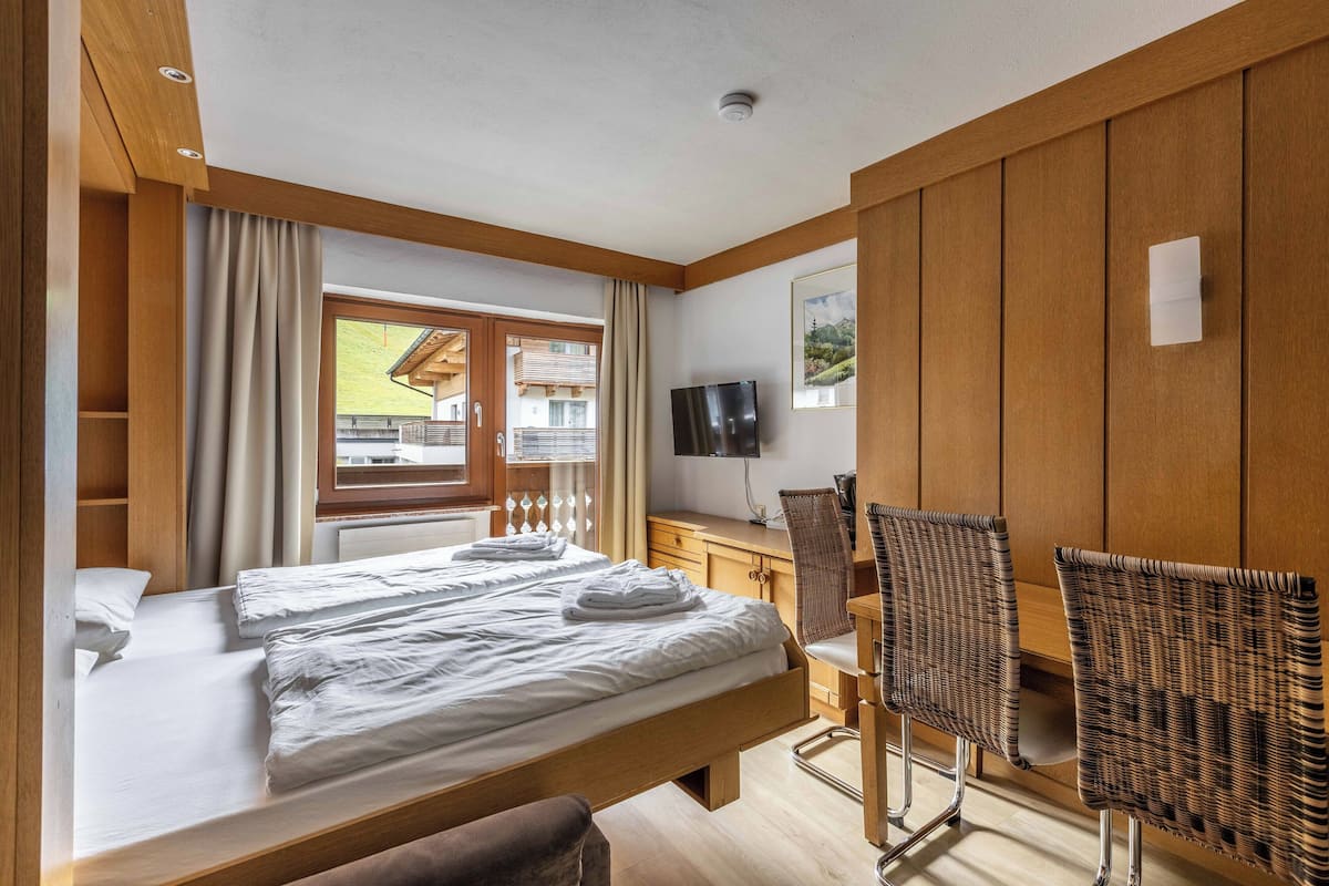 Habitación de hotel con dos camas, un escritorio, un televisor y sillas de mimbre.
