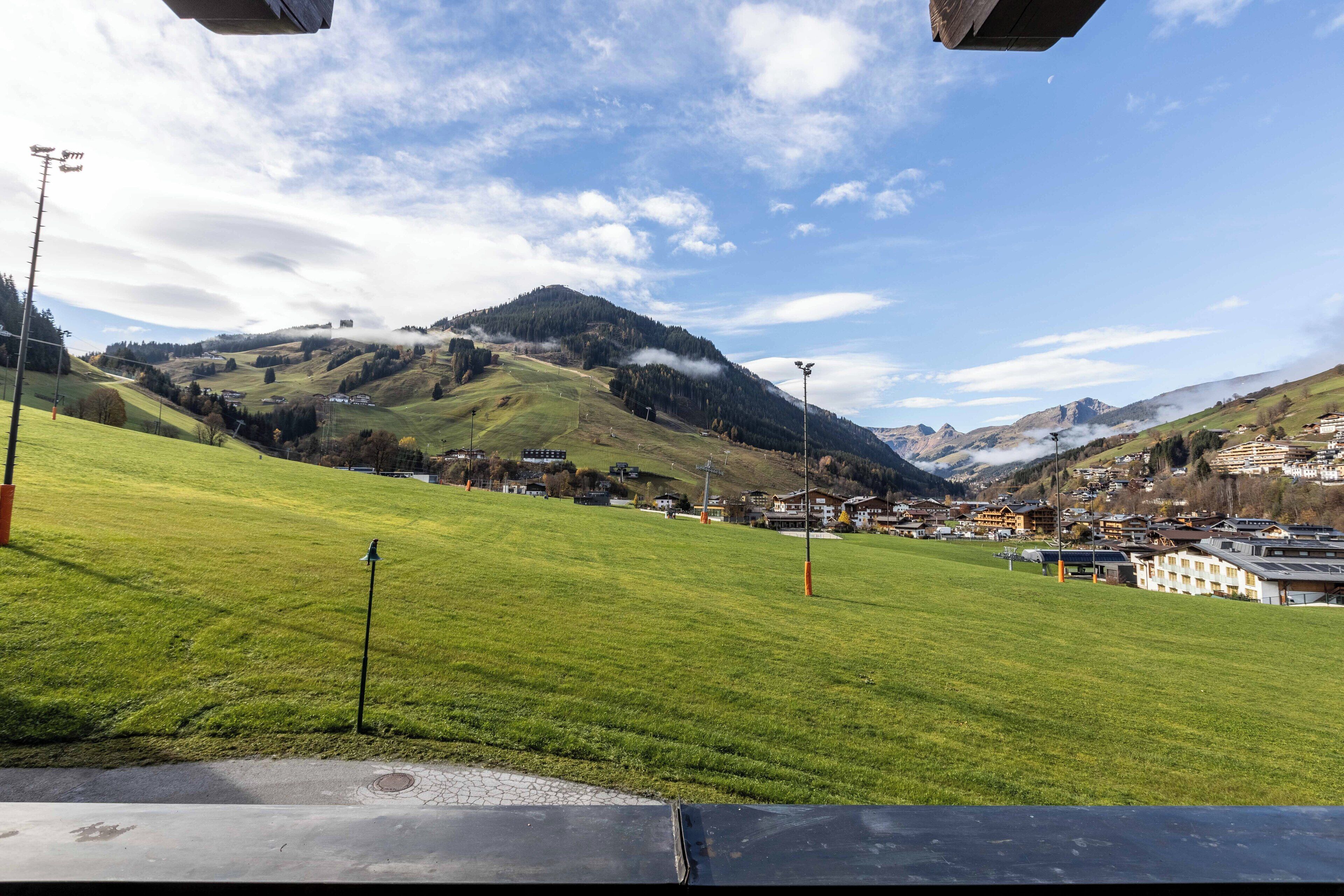 Un champ verdoyant avec une ville en arrière-plan, une montagne et un ciel dégagé.