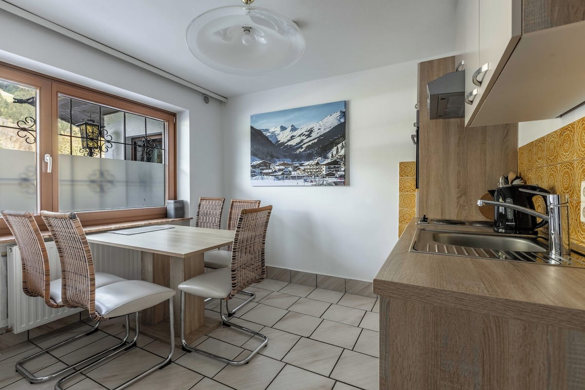 Una cocina moderna con comedor, vistas a las montañas a través de una ventana y una isla de cocina con fregadero.