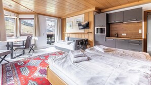 Une chambre d’hôtel moderne dotée d’un grand lit, d’un bureau et d’une kitchenette.