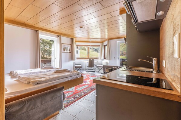 A room with two beds, a kitchen area, and a dining table.