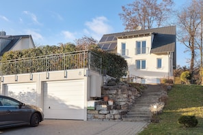 Un immeuble résidentiel doté d’un garage, d’un escalier menant à l’entrée et d’une voiture garée dans l’allée.