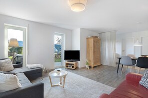 Un salon moderne comprenant un canapé, un divan rouge, un téléviseur, une table à manger et un meuble.