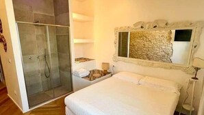 Un dormitorio con una cama grande, zona de ducha y una pared decorativa de piedra.