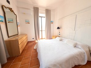 Ein Schlafzimmer mit Bett, Kommode, Spiegel und einer Wand mit geometrischem Muster.