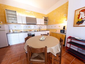 Una cocina compacta con una mesa de comedor, sillas y una estantería roja.