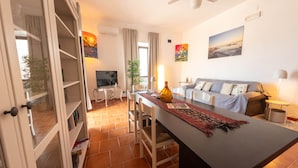 Un soggiorno moderno con zona pranzo, un divano, una televisione e una ventola a soffitto.