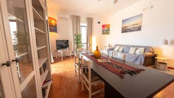 Una sala de estar moderna con comedor, sofá, televisor y ventilador de techo.