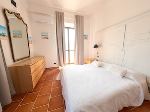 Une chambre à coucher comprenant un lit, une commode, un miroir et un mur orné d’un motif géométrique.