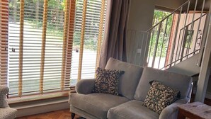A living room with a grey sofa, patterned cushions, a wooden bench, and a herringbone floor. - The Studio - A cosy studio apartment (Hungerford)