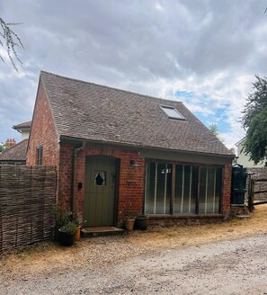 A brick building with a green door, large windows, and a gravel driveway.