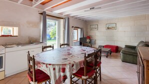 Un comedor con una mesa redonda, sillas, una cocina con un lavamanos y un sofá rojo.