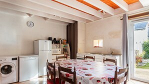 Una cocina compacta con mesa, sillas, lavadora y refrigerador.