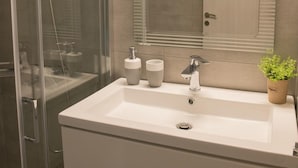 A modern bathroom with a glass-enclosed shower, a large mirror, and a white sink. - Elani Crete (Heraklion)