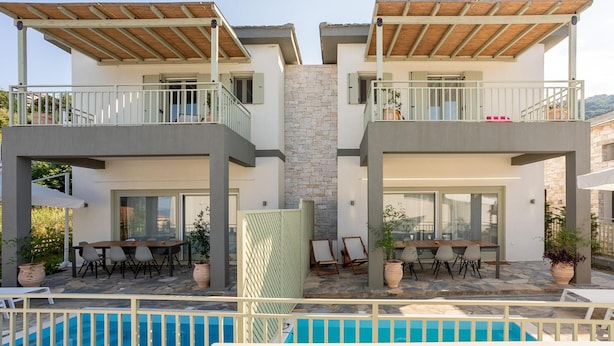 A modern two-story building with a pool, outdoor seating, and a stone facade. - Villas in Pelion (Zagora-Mouresi)