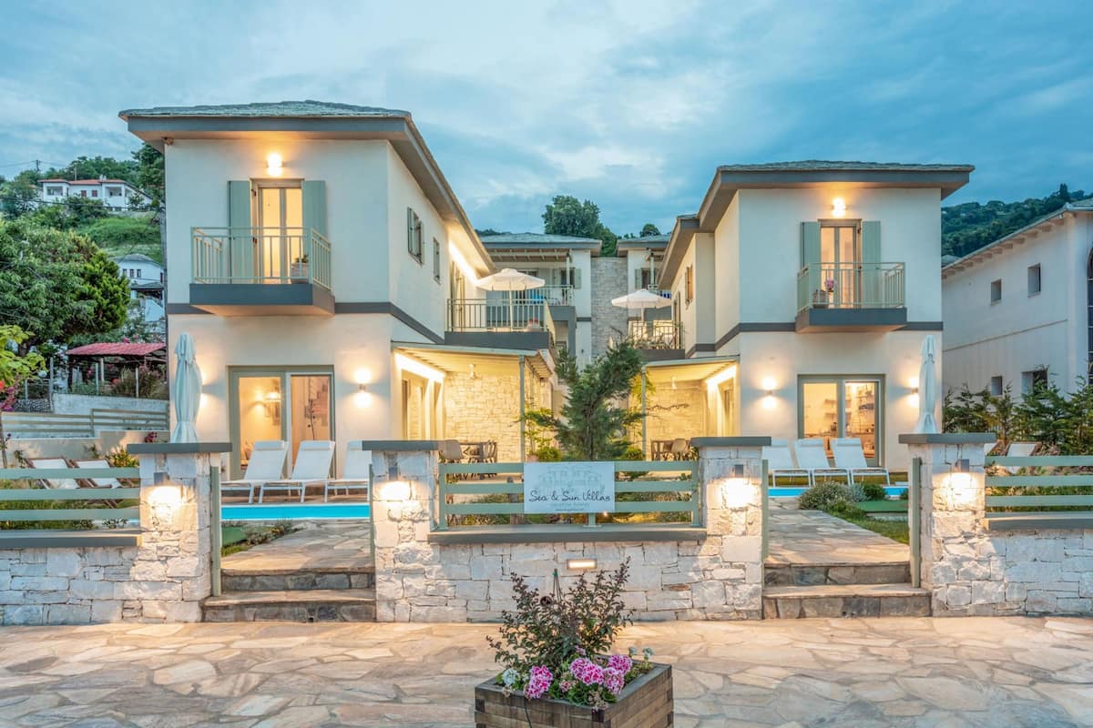A two-story villa with a pool, outdoor seating, and a stone pathway.