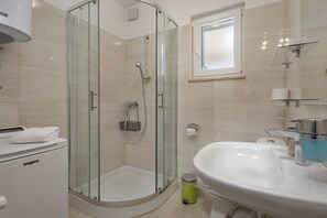 A modern bathroom with a glass-enclosed shower, a sink, and a toilet. - Seaview Pool House Mytilus (Rasa)