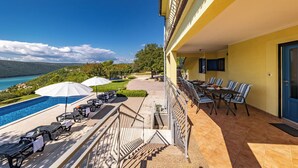 A hotel balcony with a pool, outdoor seating, and a view of the sea and mountains. - Seaview Pool House Mytilus (Rasa)