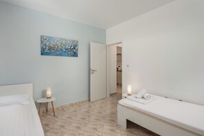 A hotel room with a bed, bedside table, lamp, and a painting on the wall. - Seaview Pool House Mytilus (Rasa)