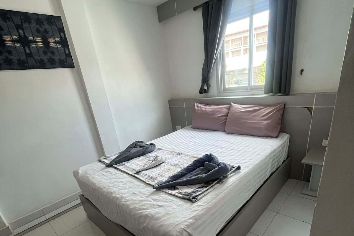 Un dormitorio con una cama, una ventana con cortinas y una obra de arte colgada en la pared.