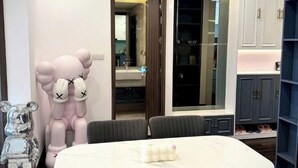 A modern room with a large mirror, a dining table, and a wardrobe with shoe storage. - X-Stay Luxe (Haiphong)